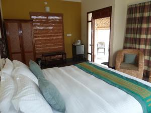 ein Schlafzimmer mit einem großen weißen Bett mit blauen Kissen in der Unterkunft Musa Jungle Retreat in Kumguri