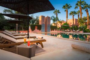 a pool with chairs and umbrellas next to a resort at Hapimag Resort Marrakesh in Douar Soukkane