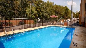 a blue swimming pool with a fence and an umbrella at Best Western Allatoona Inn & Suites in Cartersville