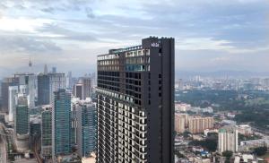 ein hohes Gebäude mitten in einer Stadt in der Unterkunft Alila Bangsar Kuala Lumpur in Kuala Lumpur