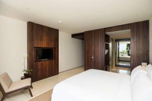 a bedroom with a bed and a tv and a chair at Studios at Alila Seminyak in Seminyak