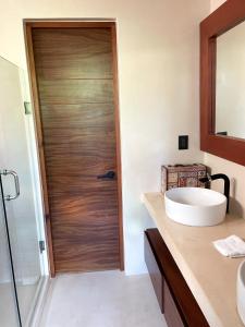 a bathroom with a wooden door and a sink at Kataleya Tulum by Zaazil - New Luxury Penthouse Up to 10 people, 3-level, 3240 sqft , Private Pool, Terrace and Roof Top in Luum Zama in the Jungle in Tulum