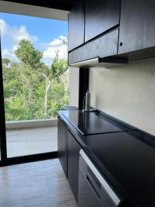 a kitchen with a black counter top and a window at Kataleya Tulum by Zaazil - New Luxury Penthouse Up to 10 people, 3-level, 3240 sqft , Private Pool, Terrace and Roof Top in Luum Zama in the Jungle in Tulum