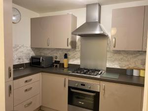 eine Küche mit weißen Schränken und einem Herd mit Backofen in der Unterkunft Spacious 2 Bed House for Corporate and Family Stays in Basingstoke