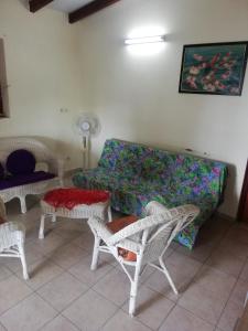een woonkamer met een bank, stoelen en tafels bij Appartement avec vue sur mer in Bouillante