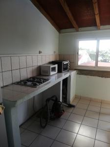 een keuken met een fornuis en een magnetron op een aanrecht bij Appartement avec vue sur mer in Bouillante