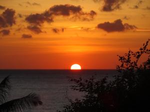 una puesta de sol sobre el océano con el sol en el horizonte en Sinar Bali 2, en Amed