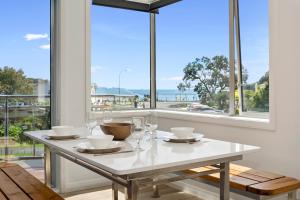 a white table with glasses and a view of the ocean at Paihia Paradise - Paihia Holiday Home in Paihia