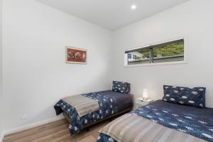 a bedroom with two beds and a window at Paihia Paradise - Paihia Holiday Home in Paihia