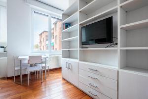 ein weißes Wohnzimmer mit einem TV und einem Tisch in der Unterkunft Nice and Cozy studio in Porta Romana by Easylife in Mailand