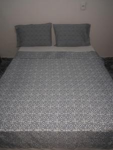 a bed with a gray and white comforter on it at HOTEL LATINOS 2 in Boa Vista