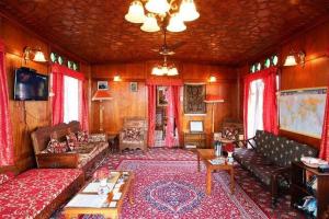 een woonkamer met banken en een tafel en een televisie bij Houseboat Lily of Nageen in Srinagar