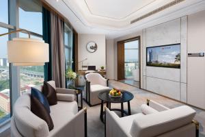 a living room with white furniture and a tv at Luzhou Jianguo Hotel in Luzhou
