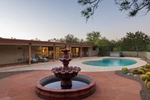 a fountain in front of a house with a pool at @TucsonMuralHouse w/pool & hot tub on golf course in Oro Valley
