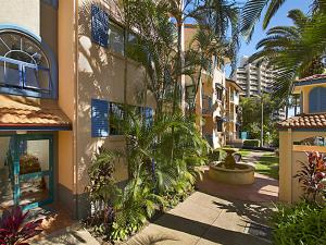 a building with a courtyard with palm trees and a fountain at Aruba Surf Resort in Gold Coast