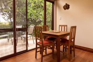 a dining room with a table and chairs and a balcony at Misty River Retreat in Blenheim