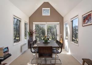 a dining room with a table and chairs and windows at Alpenglow in Dinner Plain