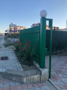una cerca verde con flores rojas junto a una puerta en Blue Sky, en Golem