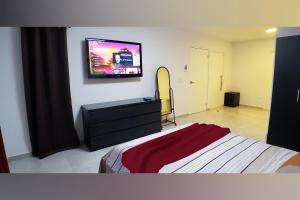a bedroom with a bed and a flat screen tv on the wall at Aruba Vacation House - Cozy and Modern! in Oranjestad
