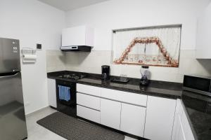 a kitchen with white cabinets and a black counter top at Aruba Vacation House - Cozy and Modern! in Oranjestad