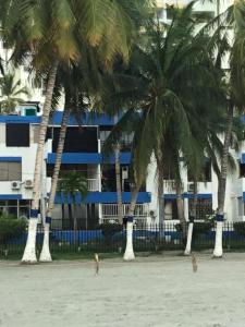 two people on a beach with palm trees and a building at PATUCA C4 in Santa Marta