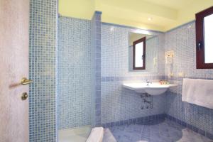 a blue tiled bathroom with a sink and a shower at Hotel Sa Pedra in Murta Maria