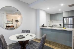 a kitchen with a table and chairs and a mirror at Meriton Suites North Sydney in Sydney