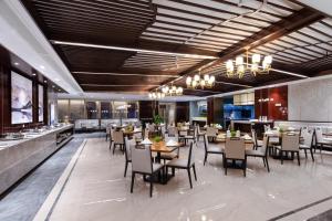 un restaurante con mesas y sillas y un bar en Luzhou Jianguo Hotel, en Luzhou