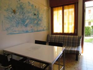 uma sala de jantar com uma mesa e uma cadeira em Lovely flat with garden and pool - Beahost em Bibione