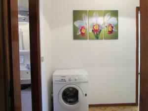 uma máquina de lavar roupa na casa de banho com duas pinturas na parede em Lovely flat with garden and pool - Beahost em Bibione