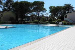 uma grande piscina com água azul em Lovely flat with garden and pool - Beahost em Bibione