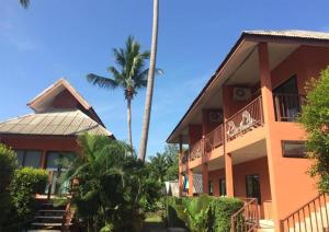 a building with palm trees in front of it at Lanta Cottage - SHA Plus in Ko Lanta