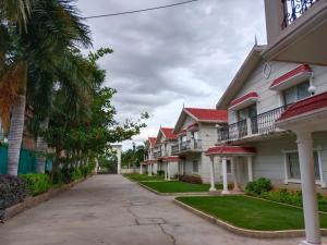 a row of houses with palm trees on a street at Sai Maa Resort And Convention Centre in Puttaparthi