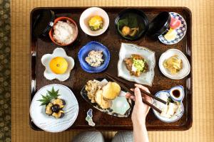 a person holding a tray of food on a table at 宿坊 端場坊｜Temple Hotel Habanobo in Minobu
