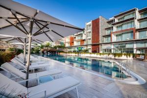 una piscina con tumbonas blancas y sombrilla en Mivara Luxury Bodrum, en Gundogan