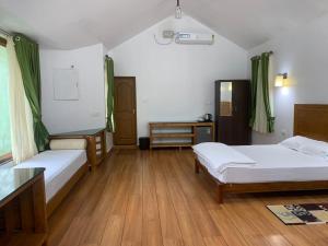 a room with two beds and a table and a mirror at Nutmeg valley in Idukki