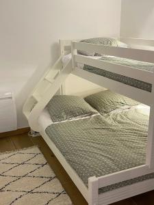 two white bunk beds in a room with a rug at L' Etoile du Pic in La Mongie