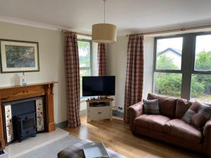 ein Wohnzimmer mit einem Sofa und einem TV in der Unterkunft Granite Cottage in Nethy Bridge