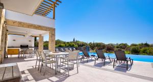 um pátio com uma mesa e cadeiras ao lado de uma piscina em Beautiful villa with great outside space - Meo, Aphrodite Hills Resort em Kouklia