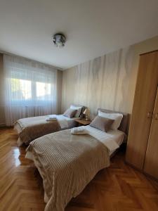 drie bedden in een kamer met houten vloeren bij Community Park Apartment in Niš