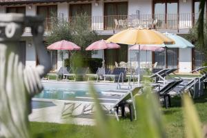 a swimming pool with umbrellas and chairs and tables at Residence Molino - Holiday Apartments in Manerba del Garda