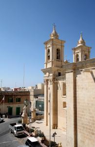 an old building with two towers and a parking lot at The King George Village Boutique Living in Għargħur