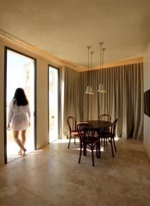 a woman walking through a dining room with a table and chairs at The King George Village Boutique Living in Għargħur