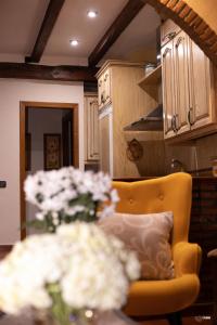 a kitchen with a yellow chair and a vase of flowers at CASA RURAL EL PIÑON in Jerte