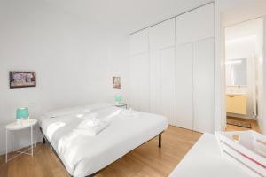 Habitación blanca con cama y espejo en Flats4Rent Delia, en Verona