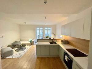a kitchen with white cabinets and a living room at Lermont Apartment old town in Bratislava