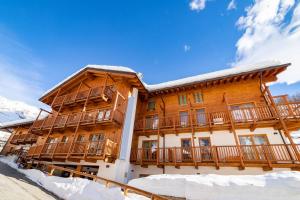 ein großes Holzgebäude mit Schnee auf dem Boden in der Unterkunft Alta Luce Mountain Lodge in Gressoney-la-Trinité