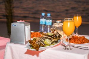 a table with a plate of food and two glasses of orange juice at New Breeze Thoddoo Inn in Thoddoo