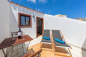un patio con 2 sedie, un tavolo e una bottiglia di vino di MEDANO4YOU Las 3 Fridas a El Médano