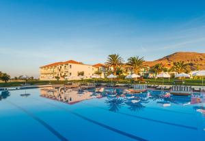 a large swimming pool with chairs and umbrellas at Aeolian Village Beach Resort in Skala Eresou